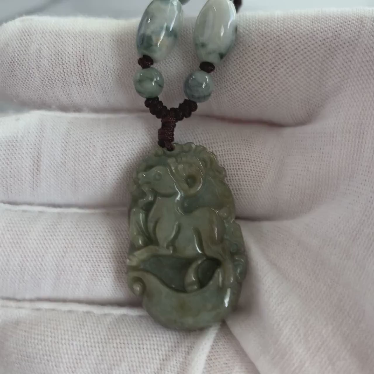 Video of hand-carved green jade Sheep pendant with gold ingot detail, elegant zodiac style and natural variations