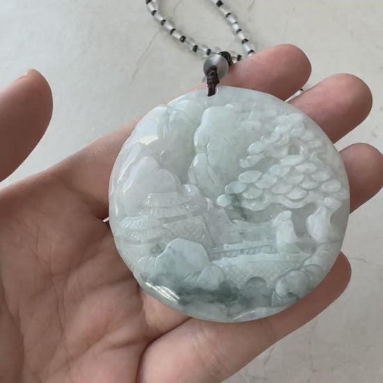 Video of a green jade pendant with intricate hand-carved mountain, forest, and riverside landscape details