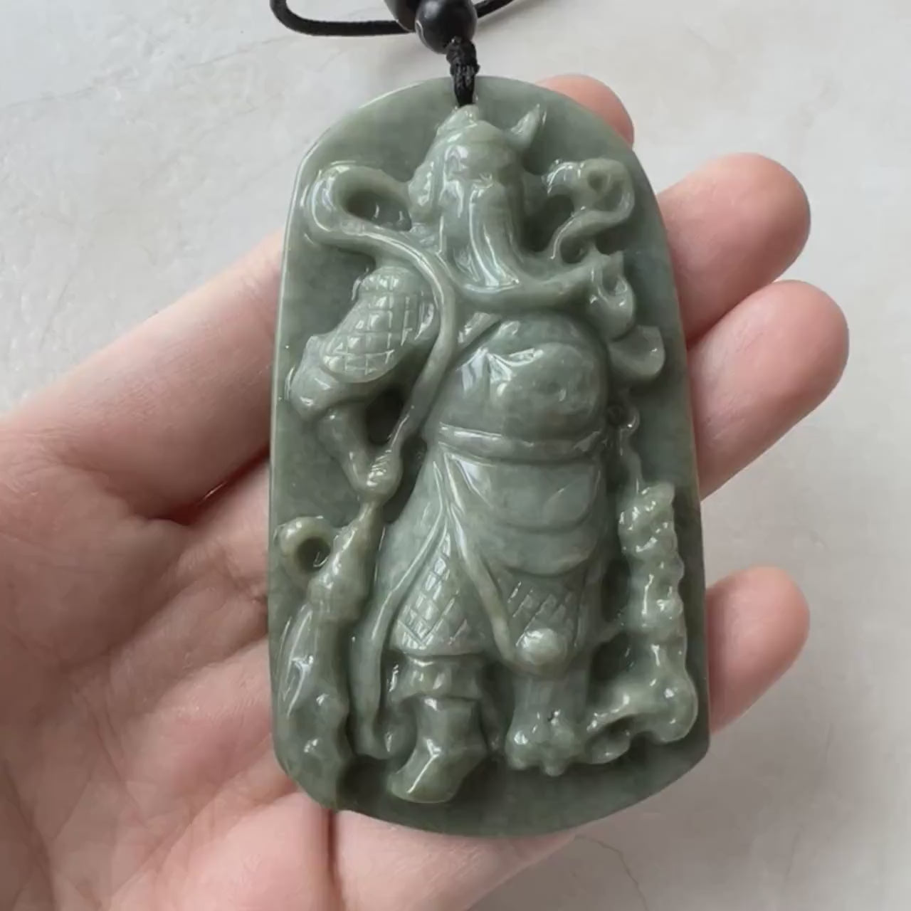 Video of a hand-carved green jadeite jade Guan Gong pendant with detailed traditional craftsmanship