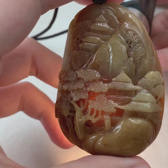 Video of a hand-carved jade pendant with red and yellow tones, autumn mountain landscape, and intricate double-sided detail