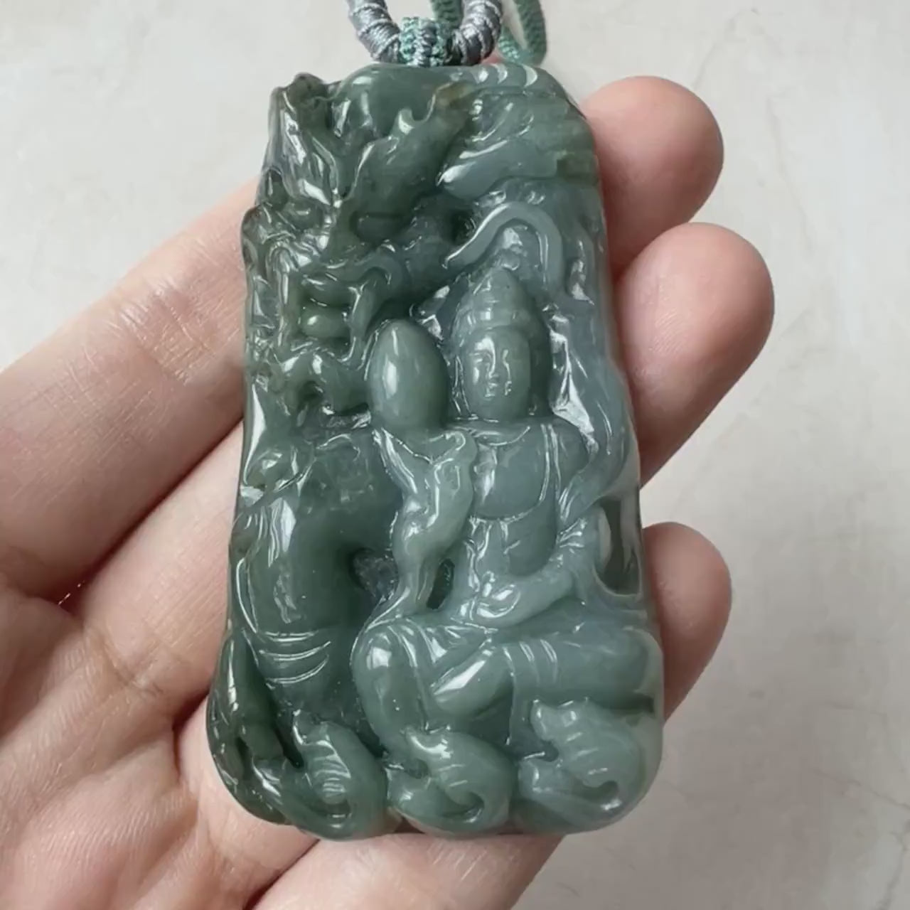 Video of hand-carved green jadeite Guan Yin pendant with protective dragon, serene and intricate fine jewelry design