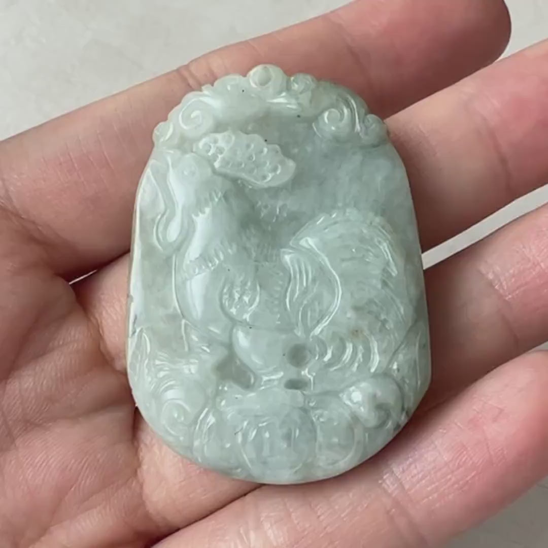 Video of hand-carved green jadeite rooster pendant on ancient Chinese coins, intricate and symbolic of prosperity