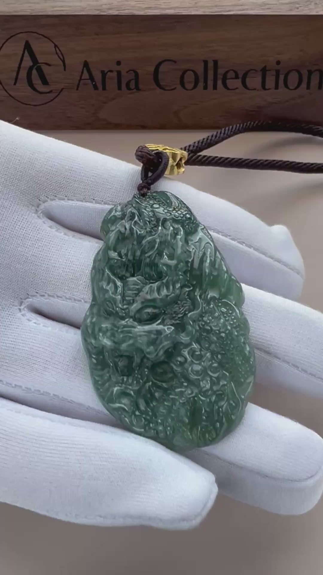 Video of a deep green natural jade pendant with pale mottling, carved Guan Gong and dragon, glossy polished finish