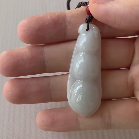 Video of a dainty hand-carved jadeite jade pea pod pendant in soft milky white with a smooth minimalist design