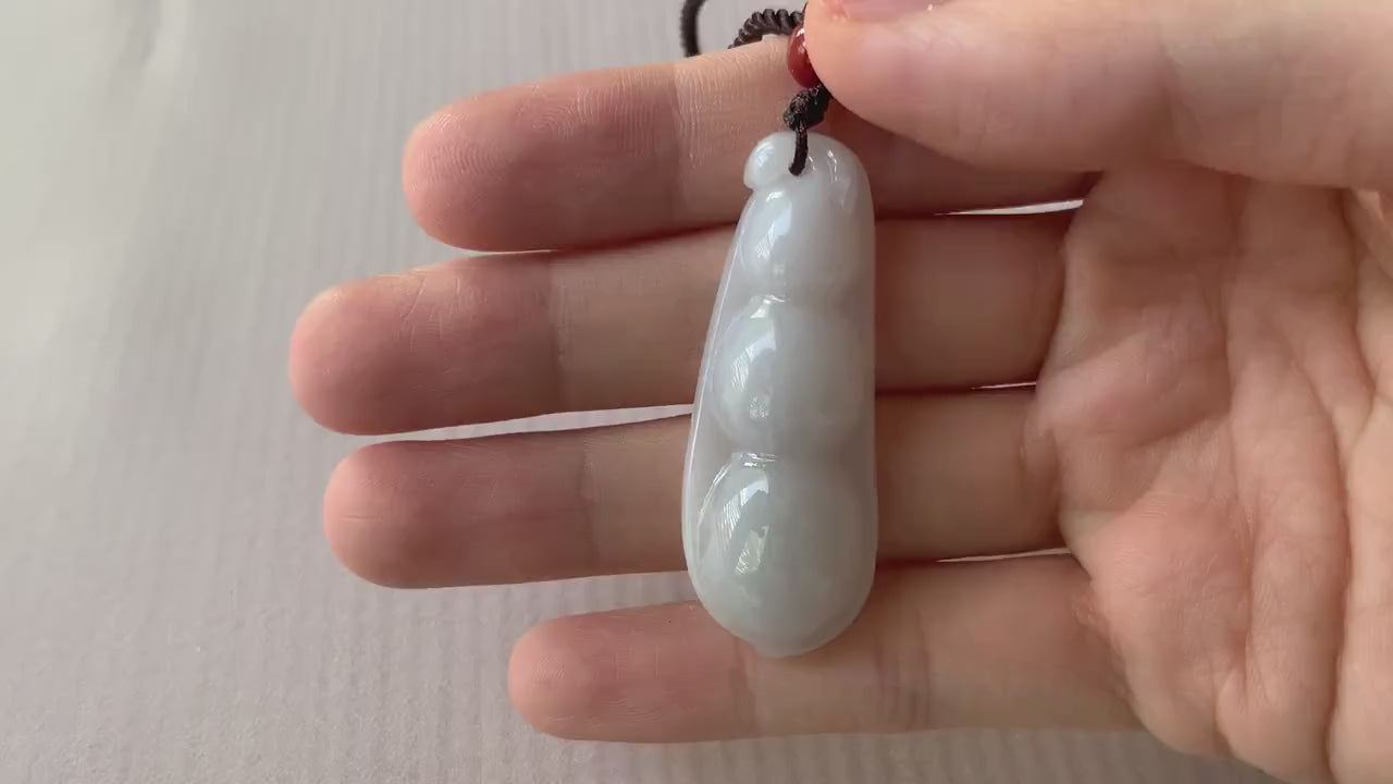Video of a dainty hand-carved jadeite jade pea pod pendant in soft milky white with a smooth minimalist design