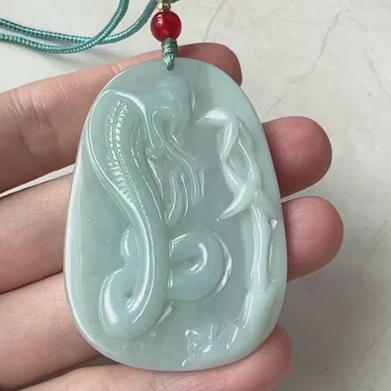 Video of a hand-carved green jade snake pendant with intricate traditional artisan detailing and forked tongue