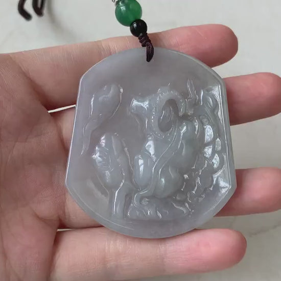 Video of a hand-carved jadeite jade Ox pendant in soft light gray-blue with a smooth, semi-translucent glow.