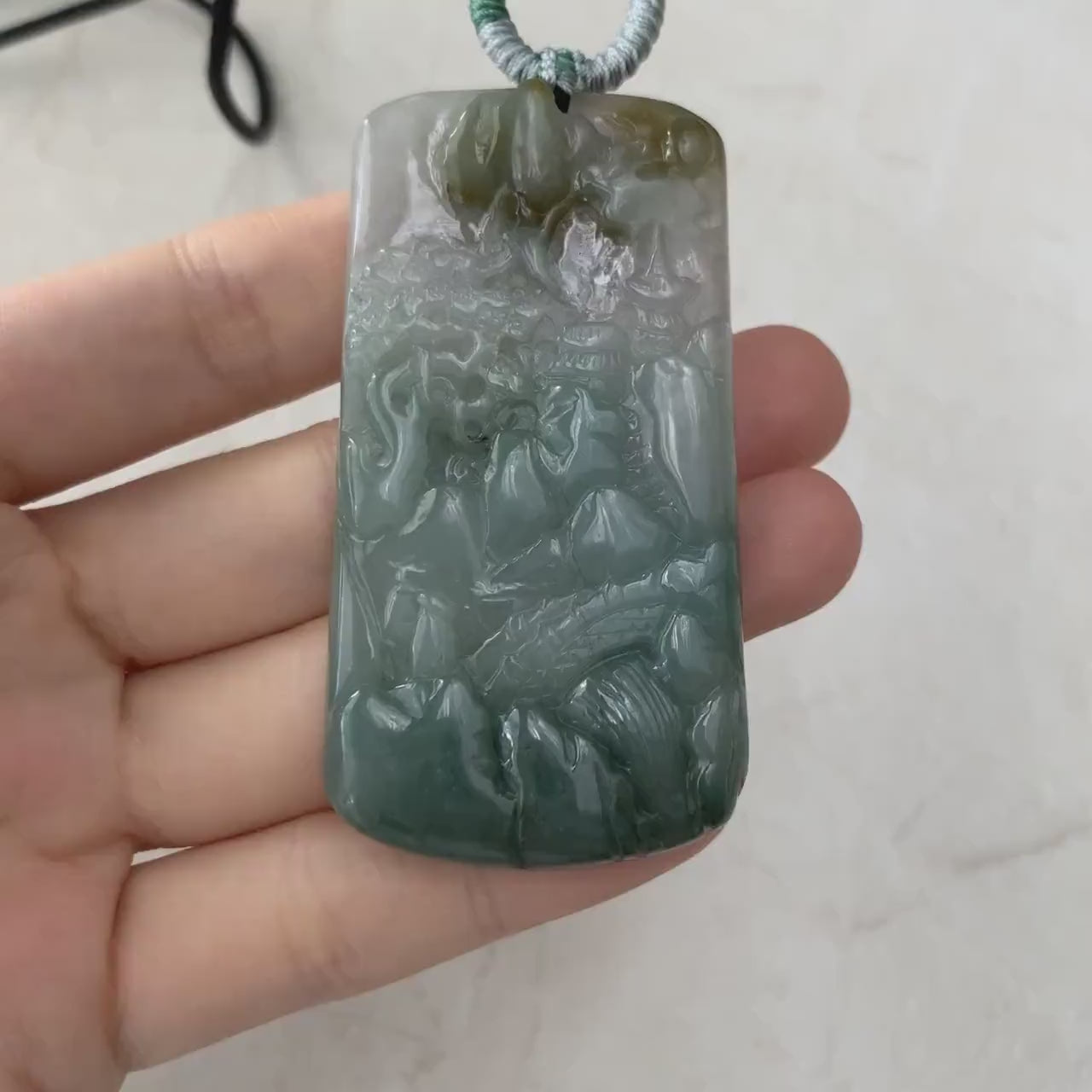Video of hand-carved dark green and yellow-green jadeite mountain landscape pendant with abstract carved back