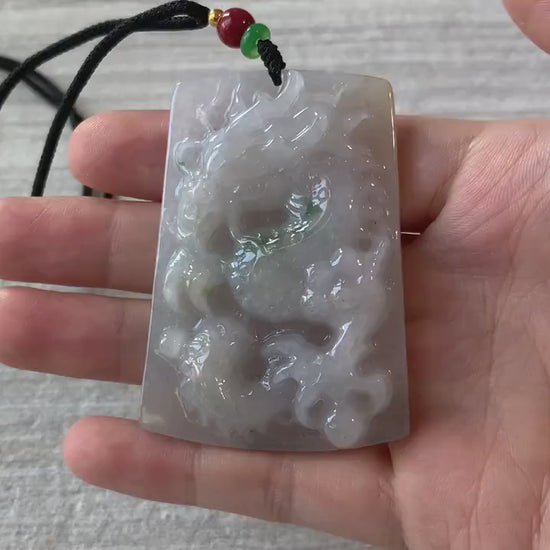 Video of a hand-carved jadeite jade dragon pendant with intricate scales, claws, and tail in rich green tones