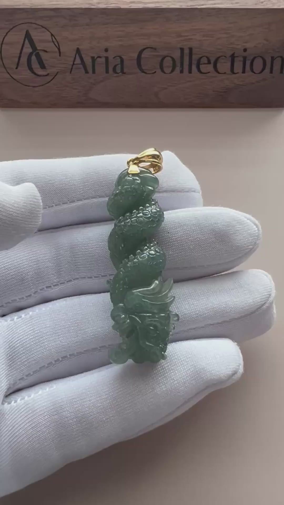 Video of an elongated deep green natural jade pendant with carved scales, polished finish, and gold-tone bail