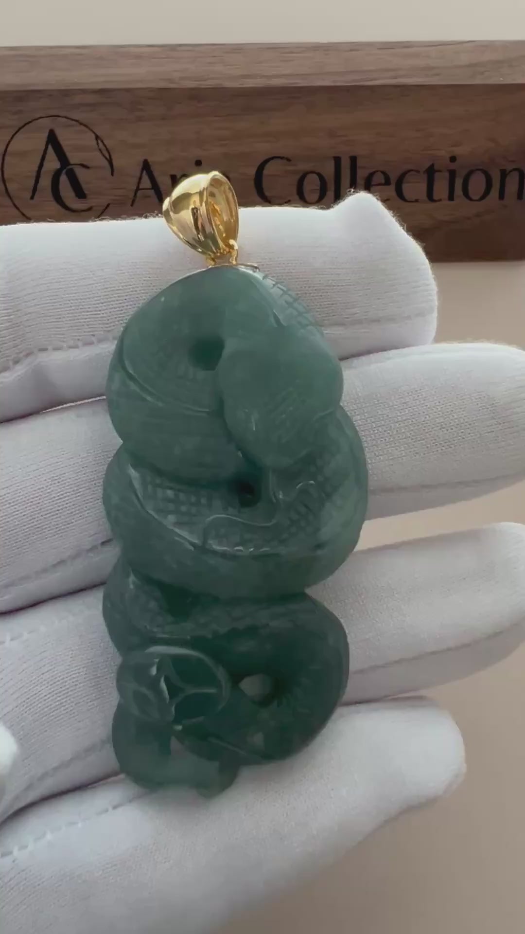 Video of a teal-green natural jade pendant with carved coiled serpent, polished finish, and gold-tone bail