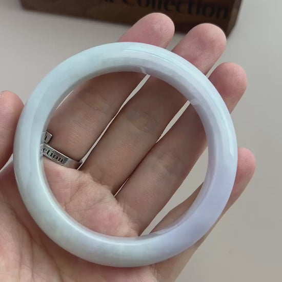 Video of an icy light blue-green Burmese jadeite bangle with soft mottling, smooth rounded profile, and high-polish finish