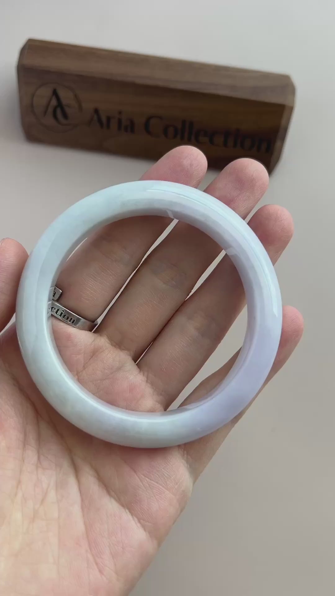 Video of an icy light blue-green Burmese jadeite bangle with soft mottling, smooth rounded profile, and high-polish finish
