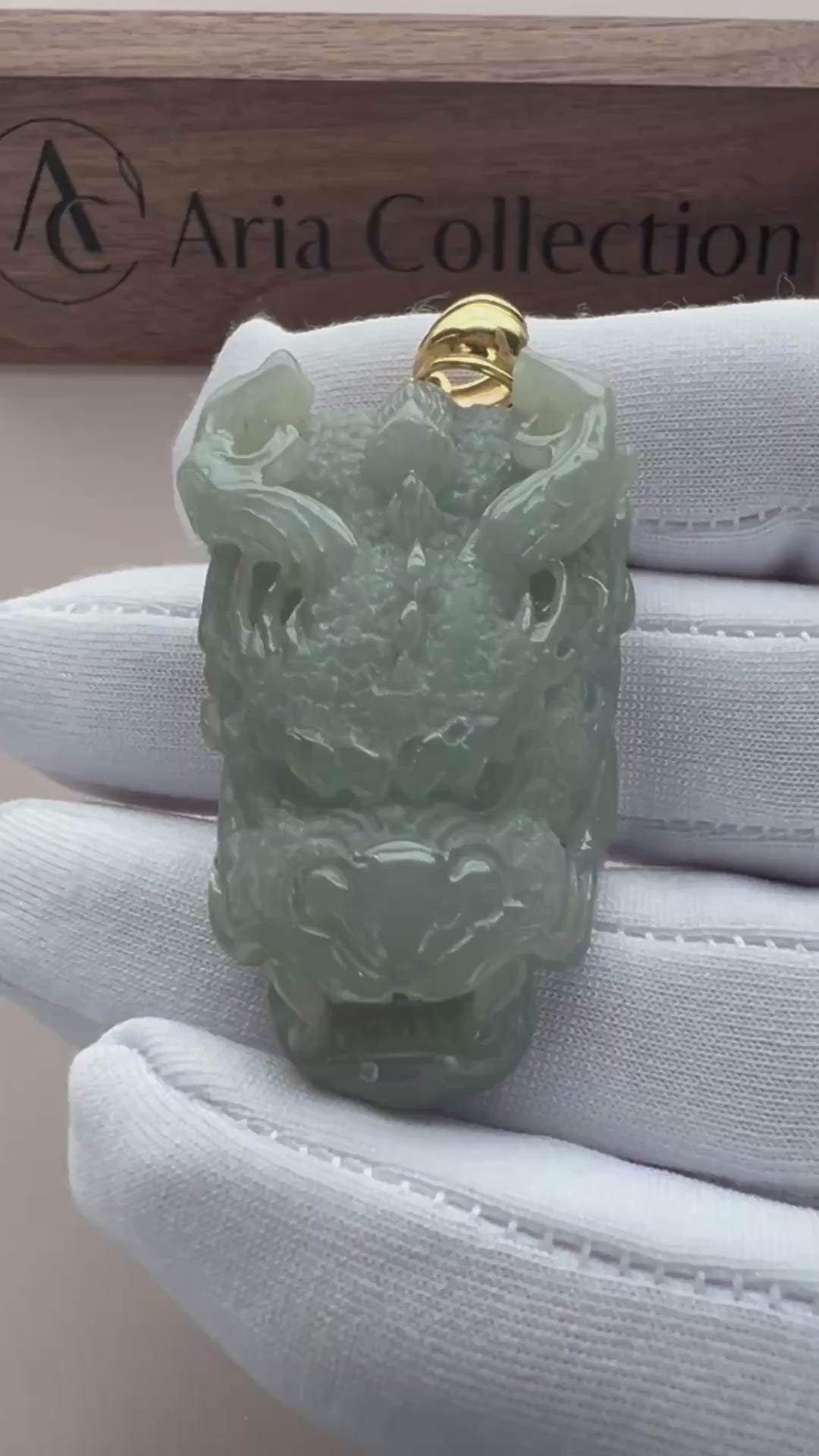 Video of pale green natural jade dragon head pendant with translucent carving, openwork details, and gold-tone bail