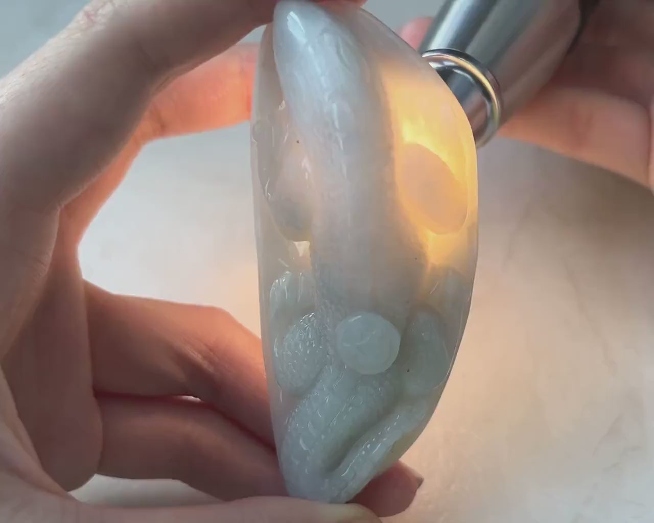 Video of a polished natural jade lizard on a leaf with carved coin detail, in refined green sculptural style
