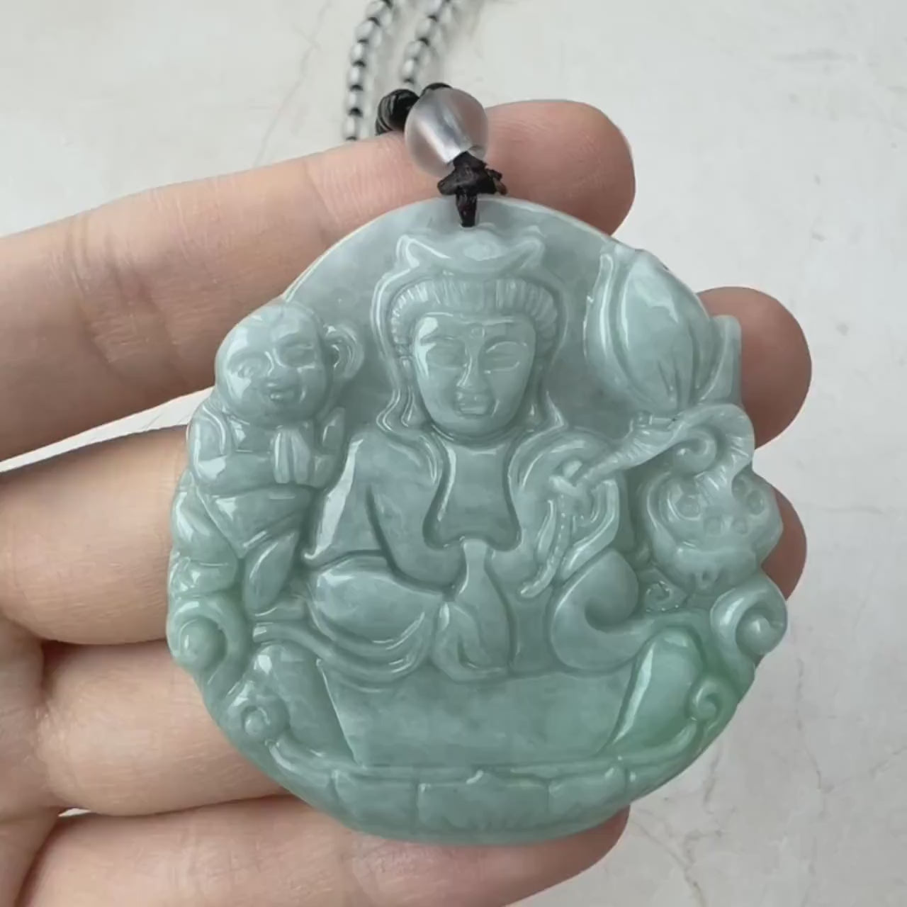 Video of hand-carved green jade Guan Yin pendant with lotus and child, on 24" necklace with clear beads