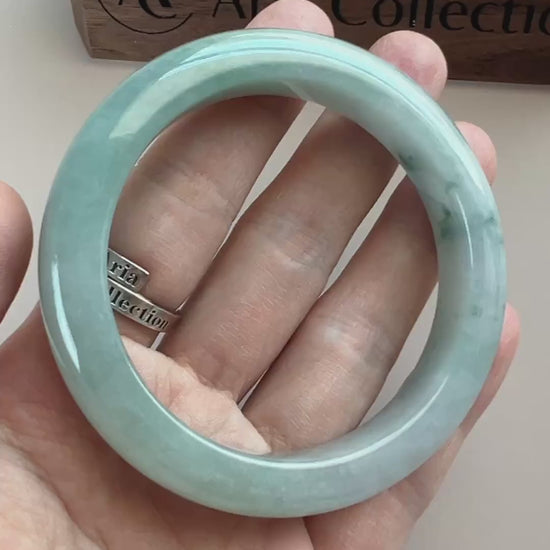 Video of a polished light blue-green Burmese jadeite bangle with cloudy variation and deep green inclusions