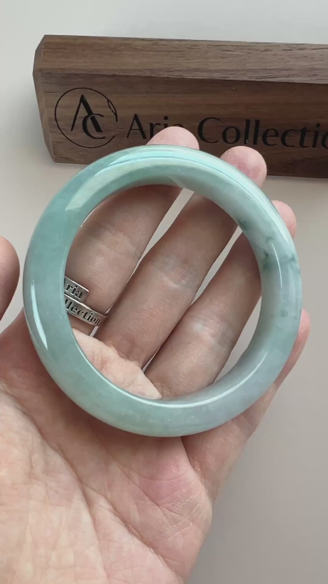 Video of a polished light blue-green Burmese jadeite bangle with cloudy variation and deep green inclusions
