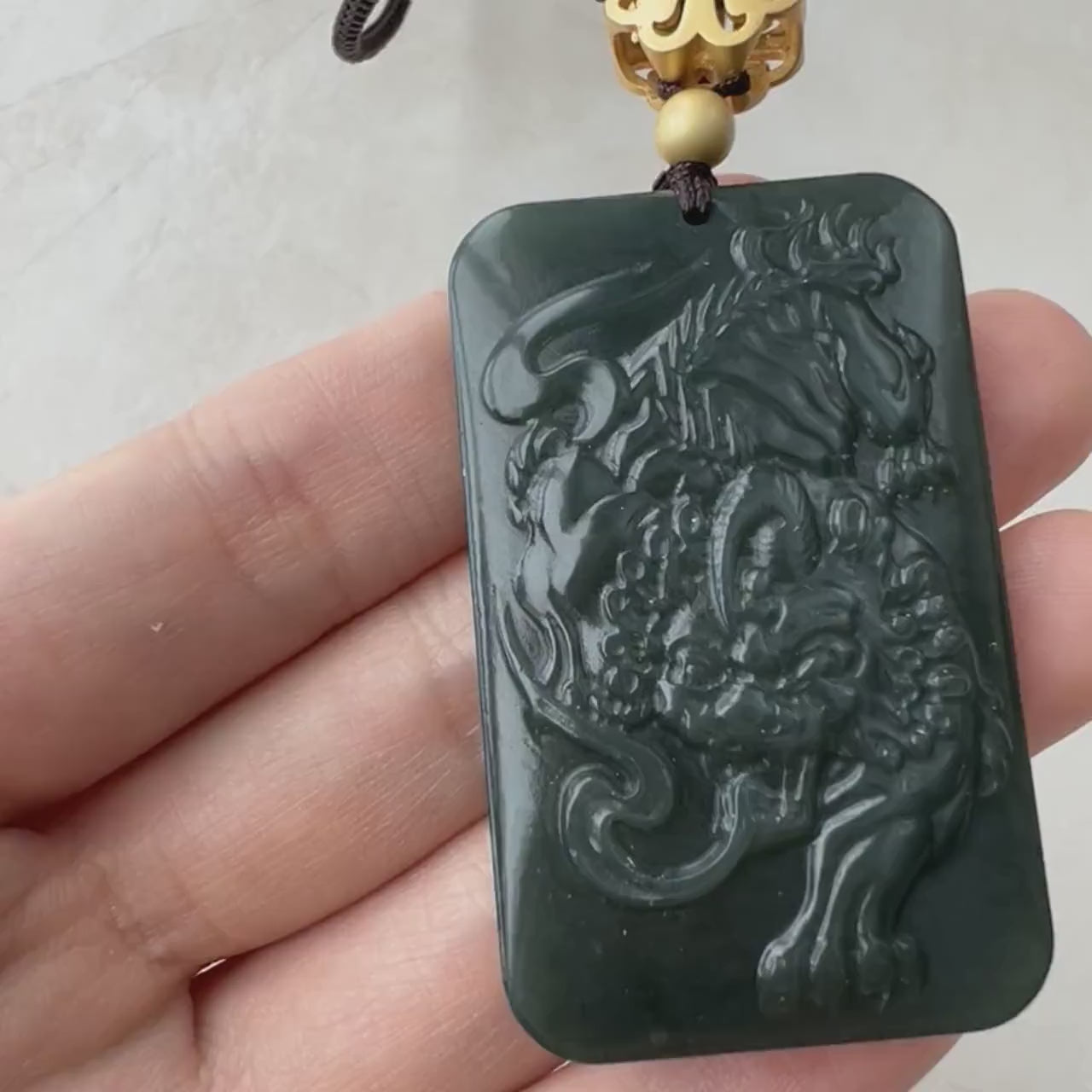Video of a hand-carved natural jadeite jade Pi Xiu pendant in green, with intricate mythical details and a fierce style