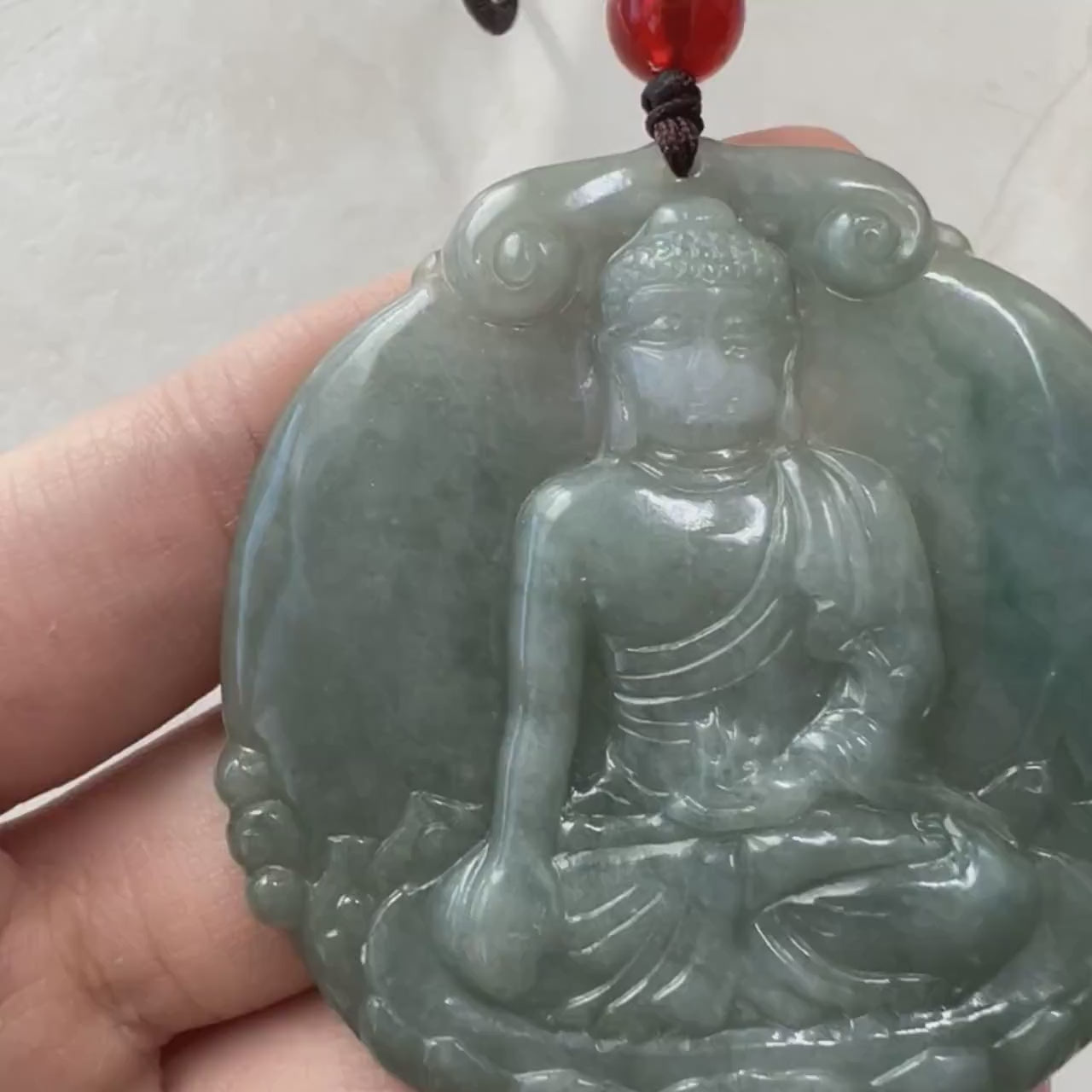Video of hand-carved natural jadeite pendant with serene Amitabha Buddha, soft green hues and luminous glow