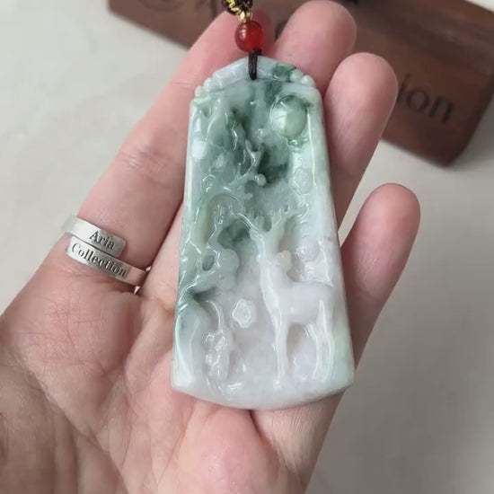 Video of hand-carved jade deer pendant in light white and green tones with a serene forest motif