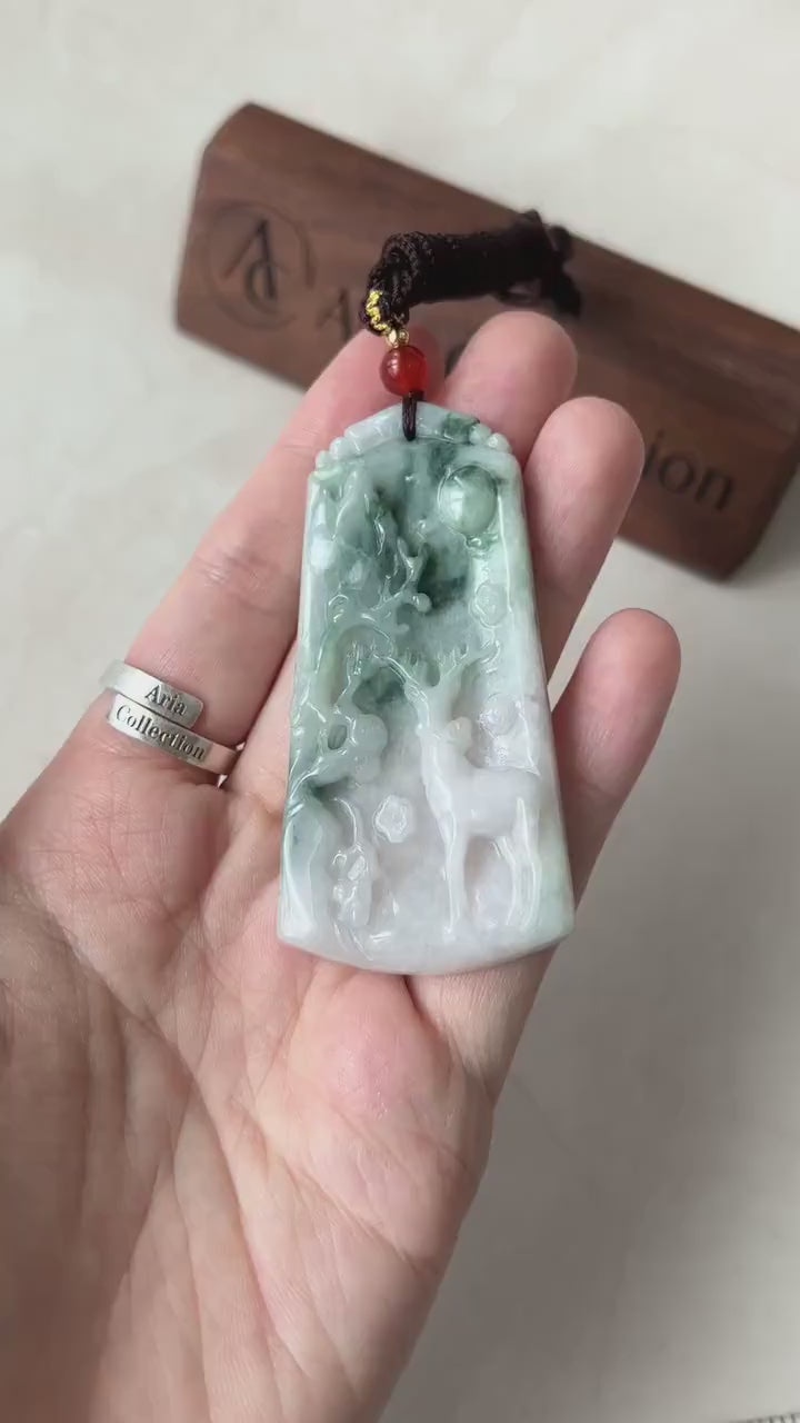 Video of hand-carved jade deer pendant in light white and green tones with a serene forest motif