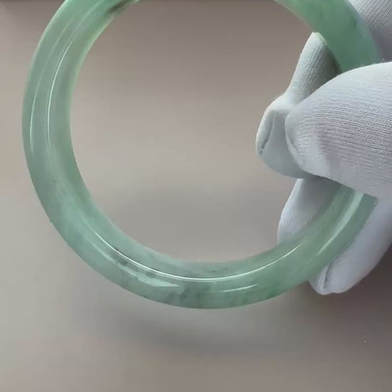 Video of a polished Burmese Type A jadeite bangle in light green with deeper green accents and a translucent rounded profile