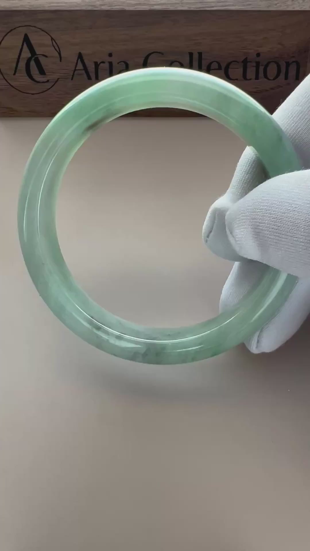 Video of a polished Burmese Type A jadeite bangle in light green with deeper green accents and a translucent rounded profile