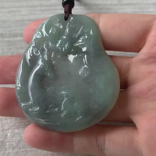Video of a hand-carved natural jadeite deer pendant in green with black splashes and a glowing translucent finish