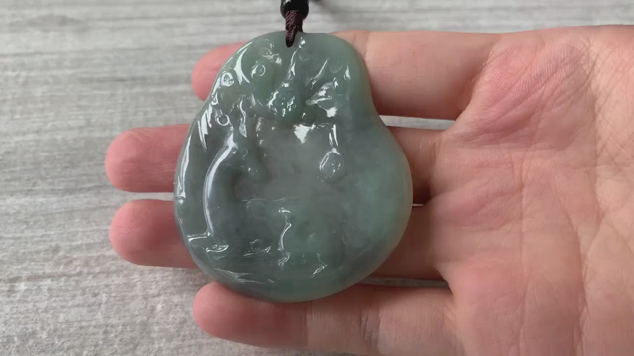 Video of a hand-carved natural jadeite deer pendant in green with black splashes and a glowing translucent finish