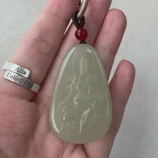 Video of a hand-carved green nephrite jade Guan Yin pendant with lotus detail, serene meditating style, and natural inclusion