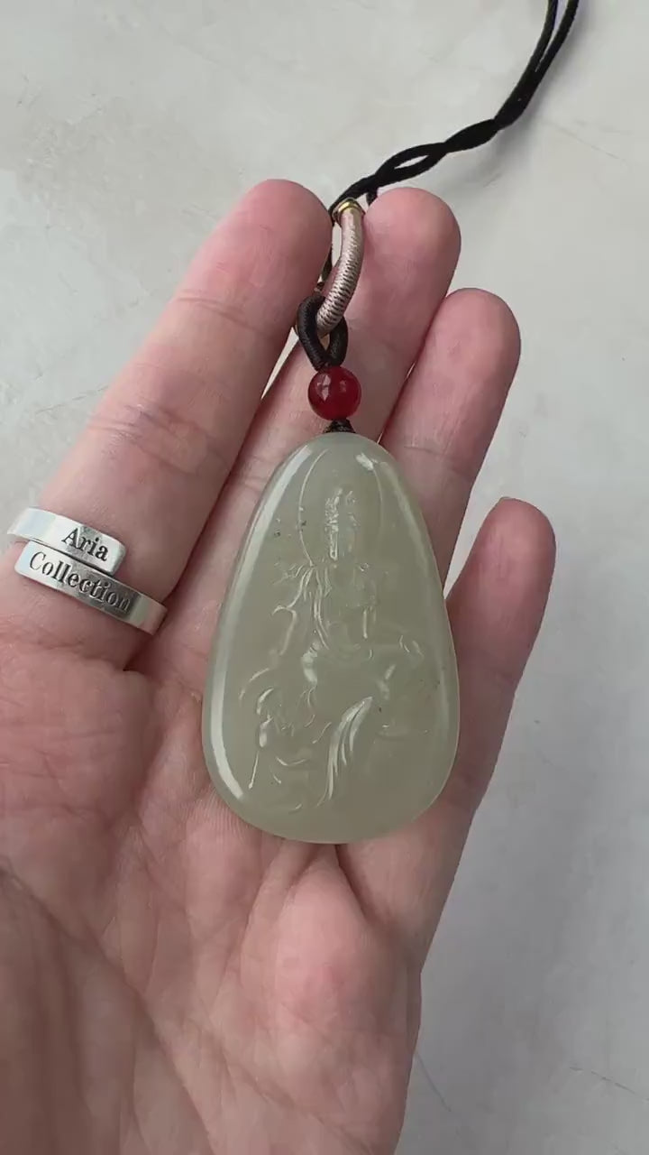 Video of a hand-carved green nephrite jade Guan Yin pendant with lotus detail, serene meditating style, and natural inclusion