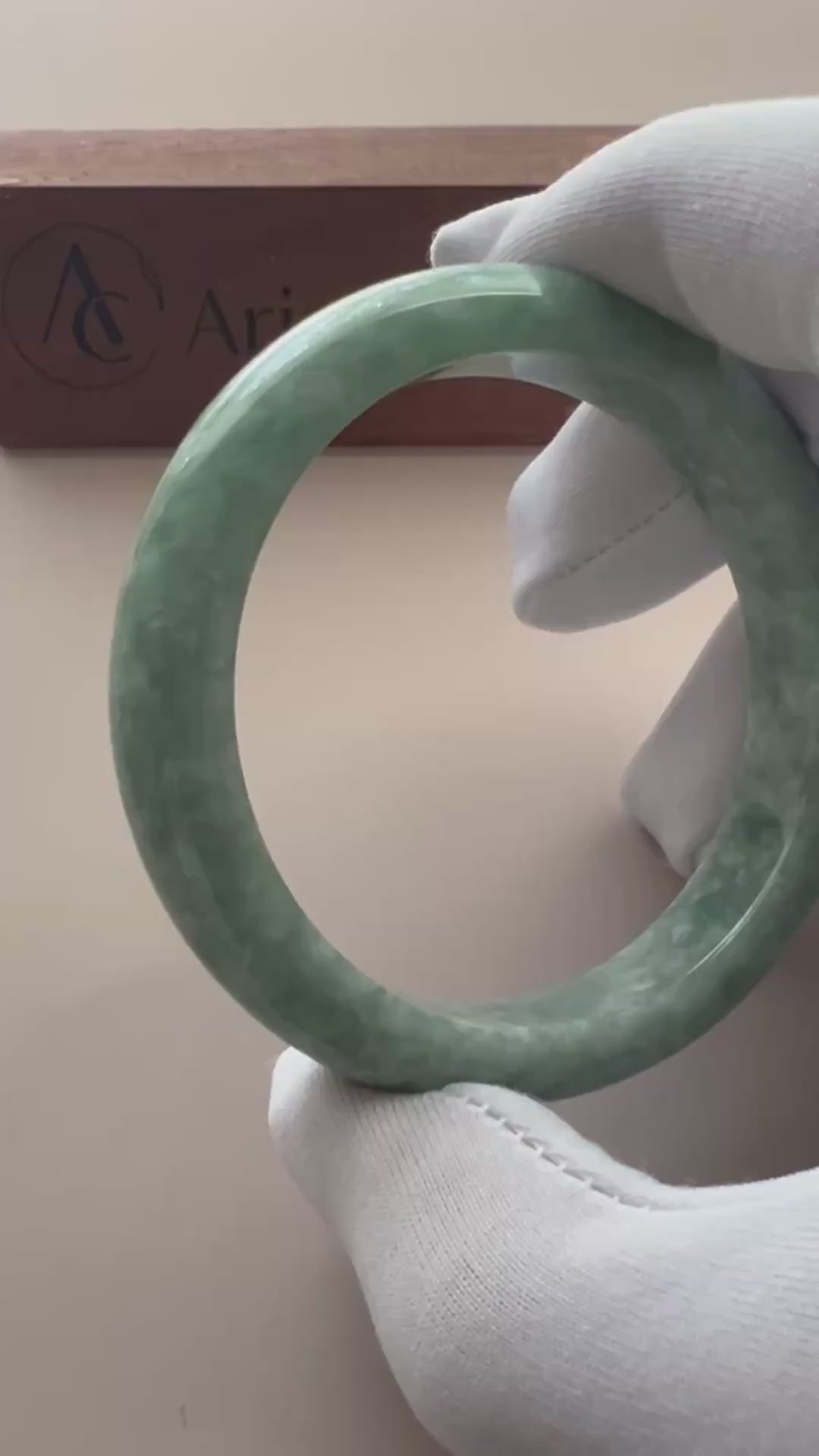 Video of a polished Burmese jadeite bangle in mottled light and medium green with a classic smooth profile