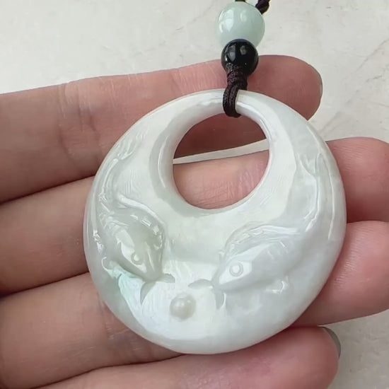 Video of hand-carved pale green and creamy white jade pendant with two fish in a circular openwork design