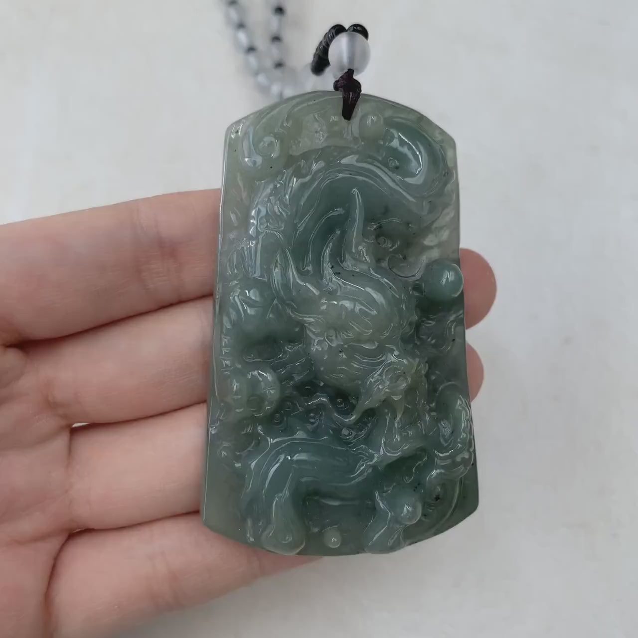 Video of a hand-carved green jadeite dragon pendant with sculpted detail and beaded necklace