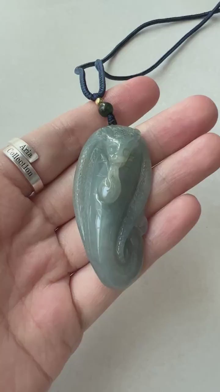 Video of a hand-carved green jadeite snake pendant with detailed scales and a soft translucent glow