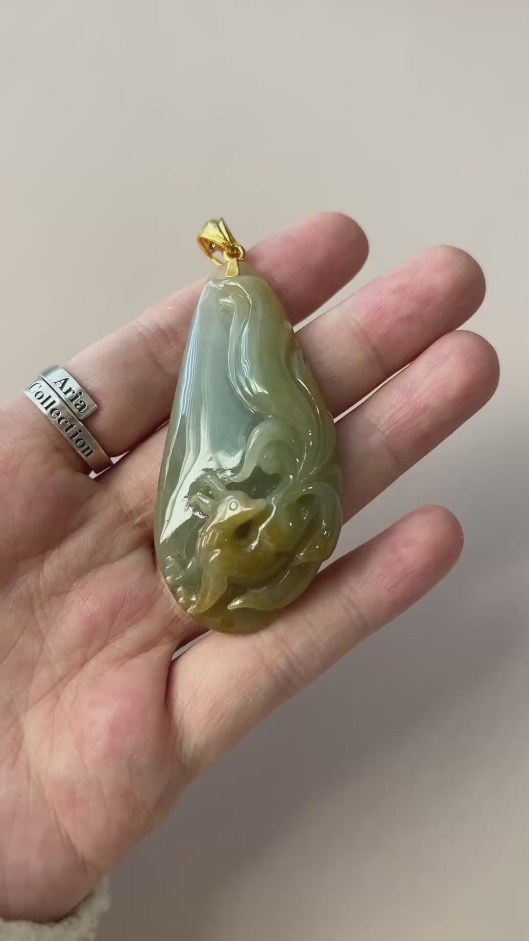 Video of a glossy light green jadeite teardrop pendant with raised fox carving and gold-tone bail