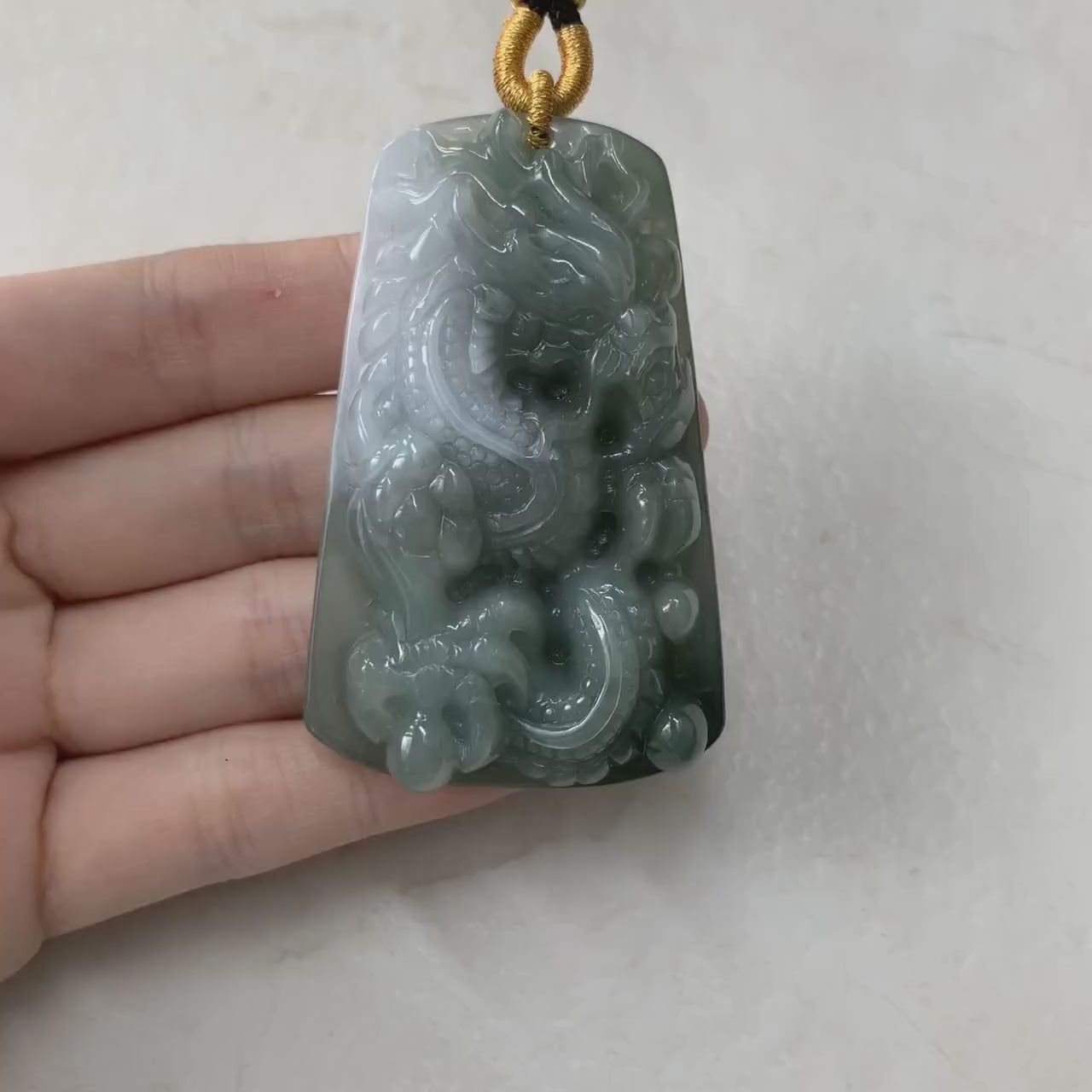 Video of a premium green jadeite pendant with an intricately hand-carved Chinese dragon design and decorative border