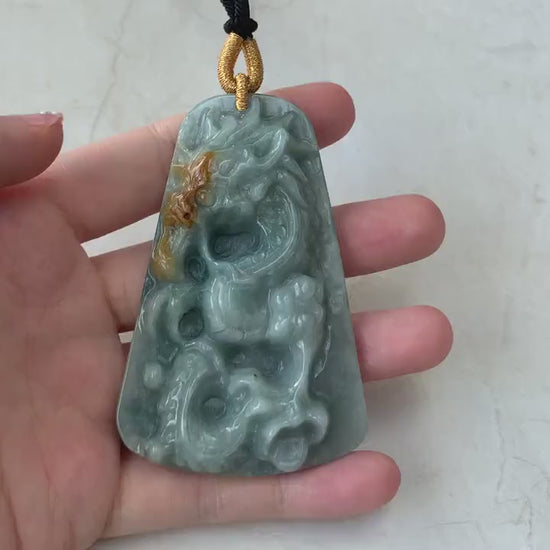 Video of natural green jadeite pendant with hand-carved dragon motif, detailed scales, claws, and tail, elegant and bold