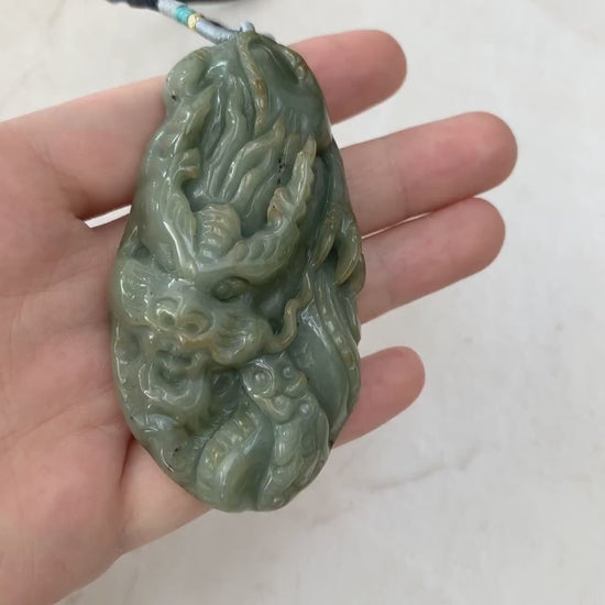 Video of a hand-carved green jadeite dragon pendant with intricate scales, claws, and flowing tail