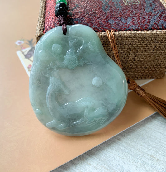 Close-up angled view of pale green jadeite deer pendant with glossy carved forest texture on cord necklace