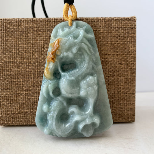 Close-up front view of hand-carved jadeite pendant necklace with glossy dragon relief and woven cord