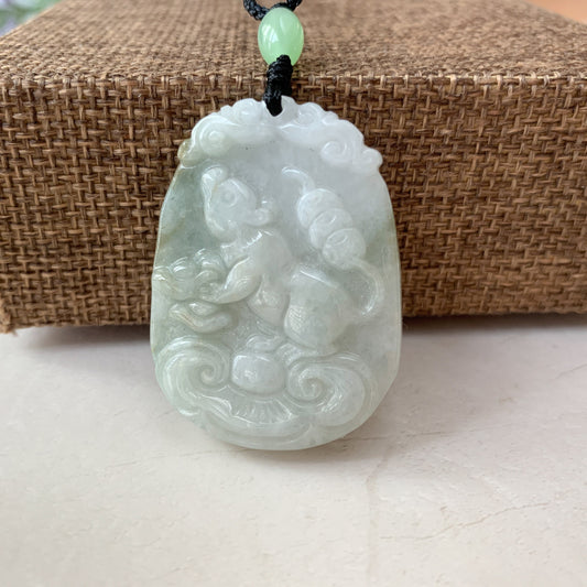 Front view of carved pale green jadeite rat pendant necklace with glossy finish and black cord on woven backdrop