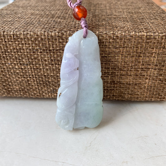 Close-up of hand-carved jadeite jade bamboo pendant with polished dual-tone finish and cord bead detail