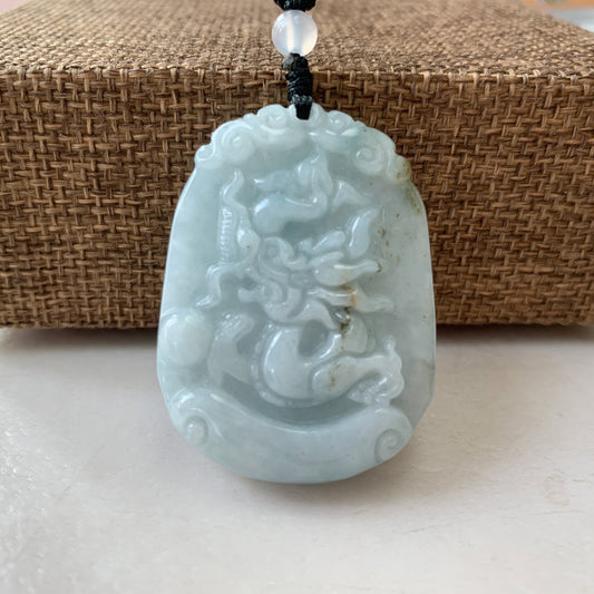 Close-up front view of pale jade dragon pendant necklace with glossy hand-carved relief and beaded cord