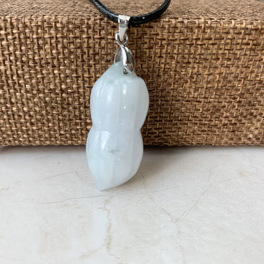 Close-up of glossy jadeite jade peanut pendant on black faux leather cord with silver bail against woven backdrop