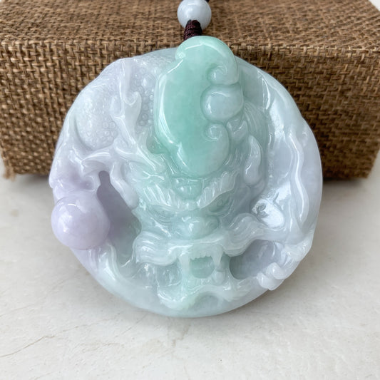 Close-up of hand-carved purple green jadeite dragon pendant with glossy polished finish and braided cord loop