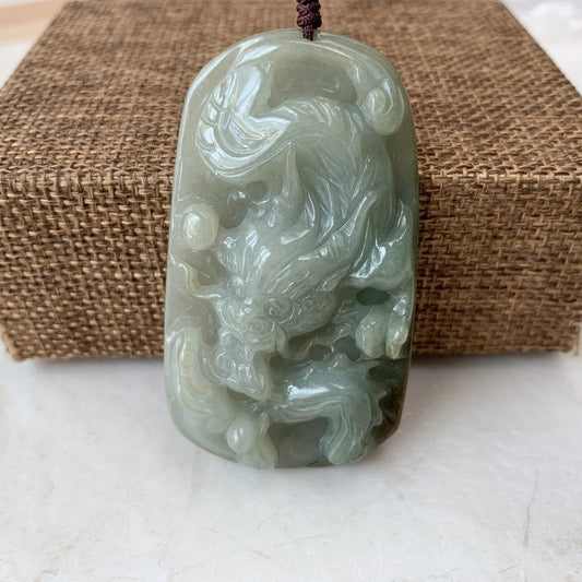 Hand-carved jadeite jade dragon pendant necklace, glossy pale green stone with detailed relief carving, front view