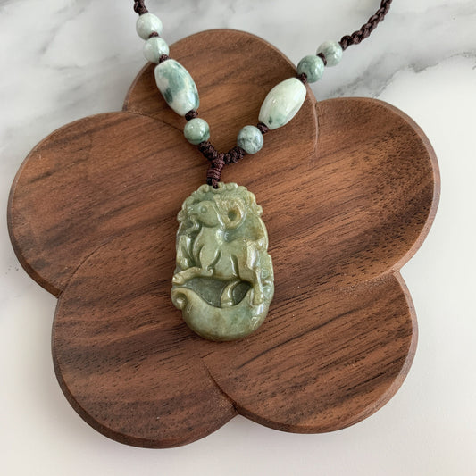 Green jadeite carved sheep pendant necklace with polished beads, shown on a wooden display board, close-up angle