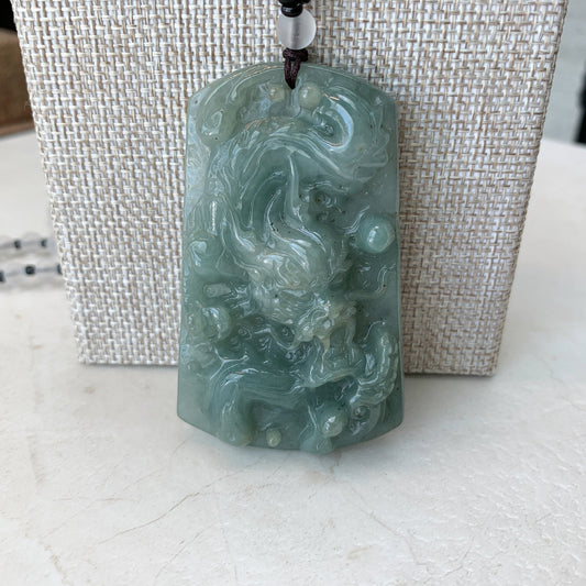 Front view of large pale green jadeite dragon pendant necklace, glossy hand-carved textured jade on cord display